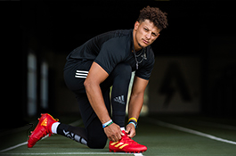 1UP Sports Marketing client Patrick Mahomes kneeling while tying his adidas shoes