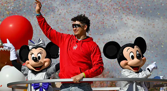 1UP Sports Marketing client Patrick Mahomes waving as he stands next to Disney characters