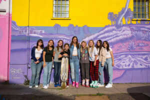 Alex Morgan standing against a wall surrounded by young girls