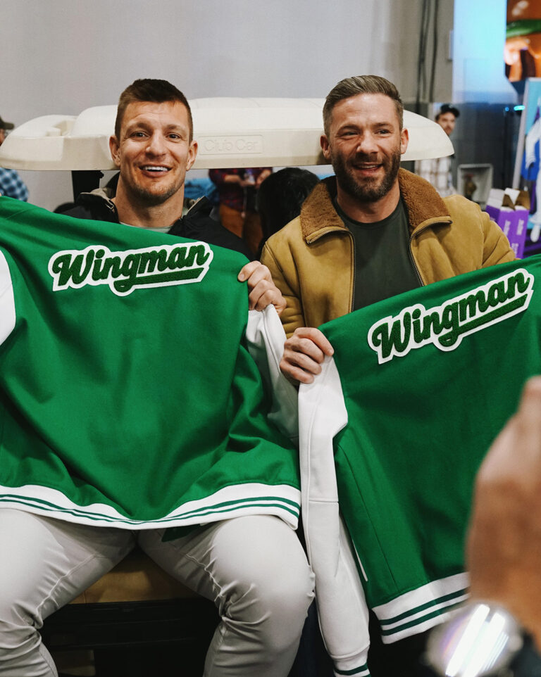 1UP Sports Marketing client Julian Edelman and Rob Gronkowski holding up their "Wingman" letter jackets