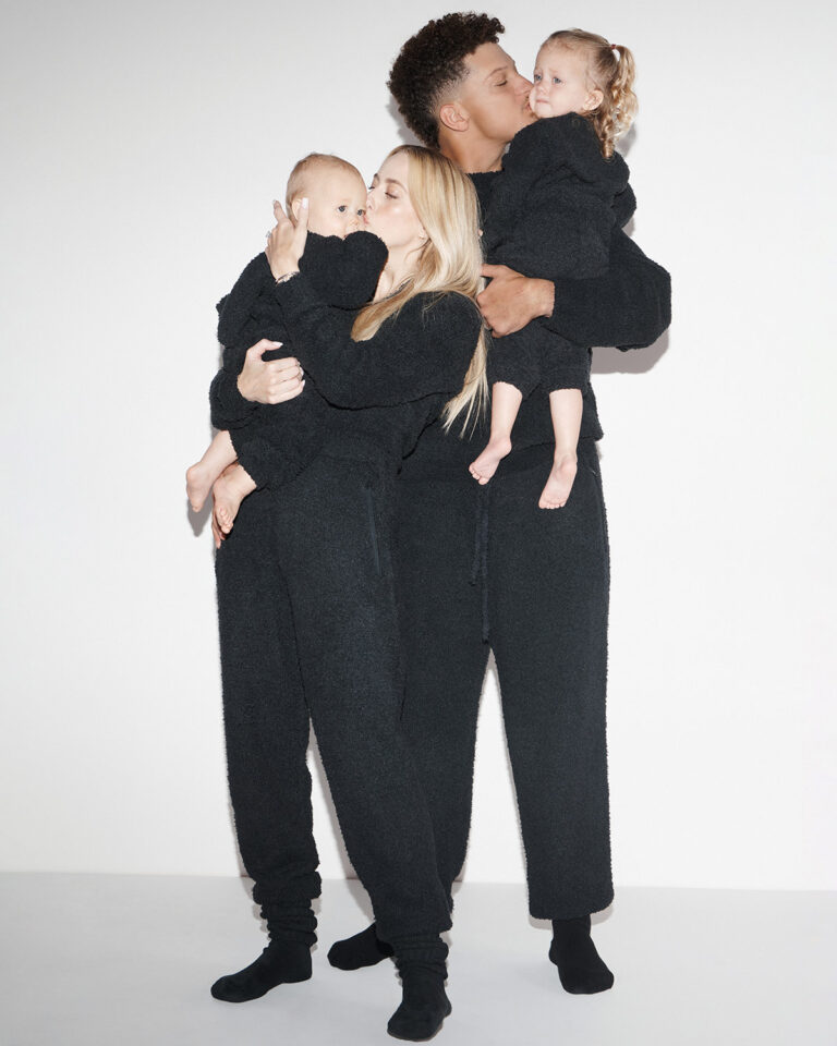 1UP Sports Marketing clients Patrick and Brittany Mahomes stand and hold kids in black onesies by SKIMS